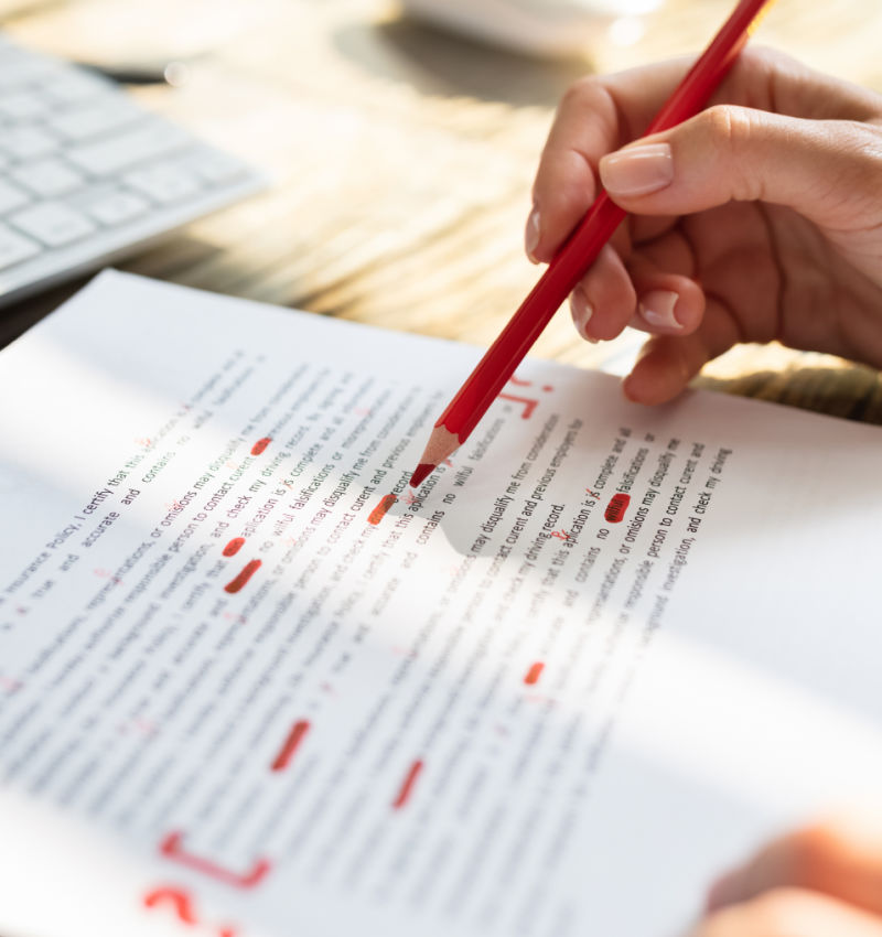 Close-up Of A Person's Hand Marking Error With Red Marker On Document